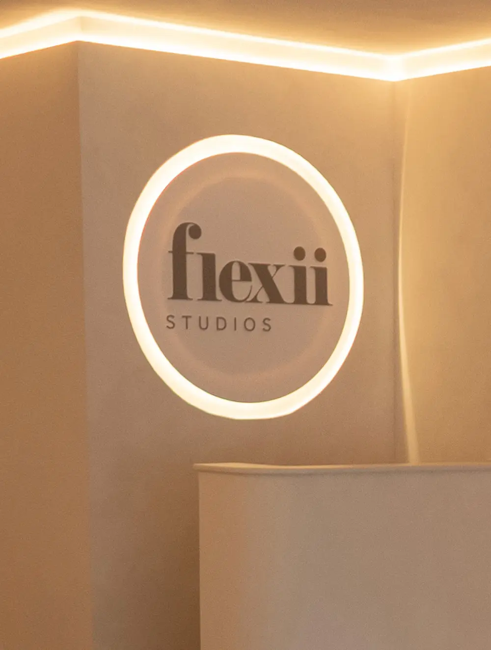 The illuminated Flexii Studios logo on the reception wall