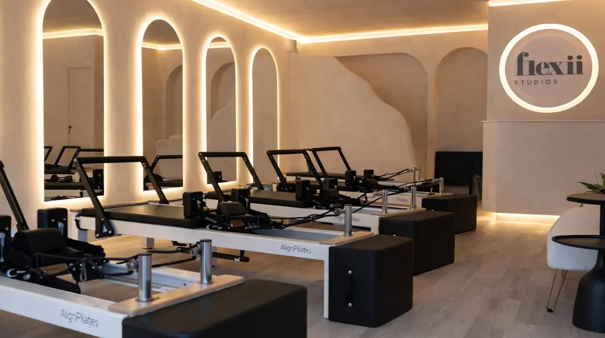 The Flexii studio with illuminated arched mirrors, reformer machines and the glowing Flexii logo