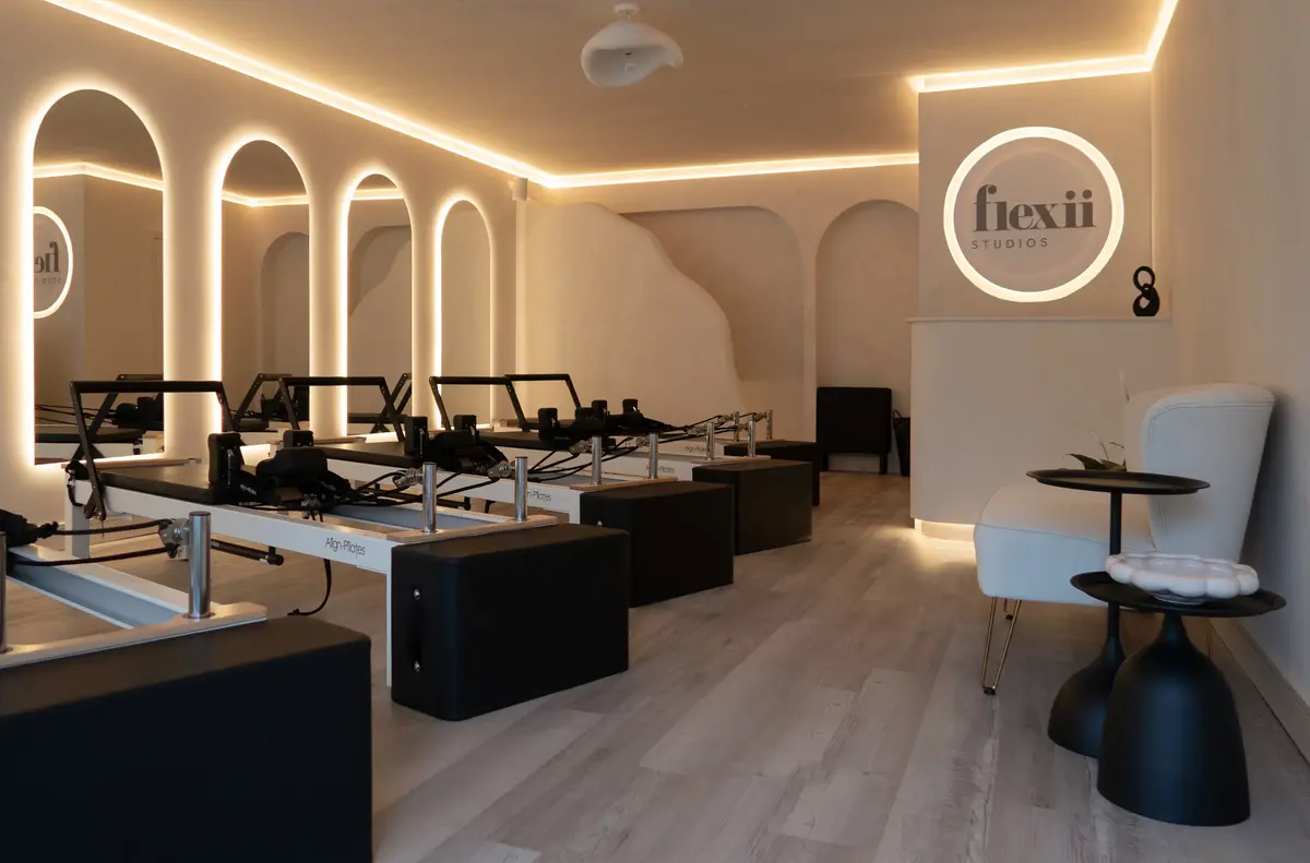 Inside Flexii Studios: reformer machines lined up beside a cream armchair, lit by warm light