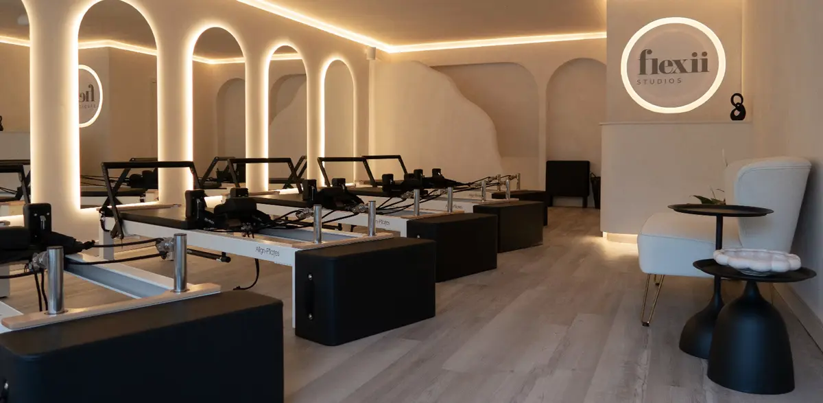 The Flexii studio: reformer machines beneath softly lit arched mirrors
